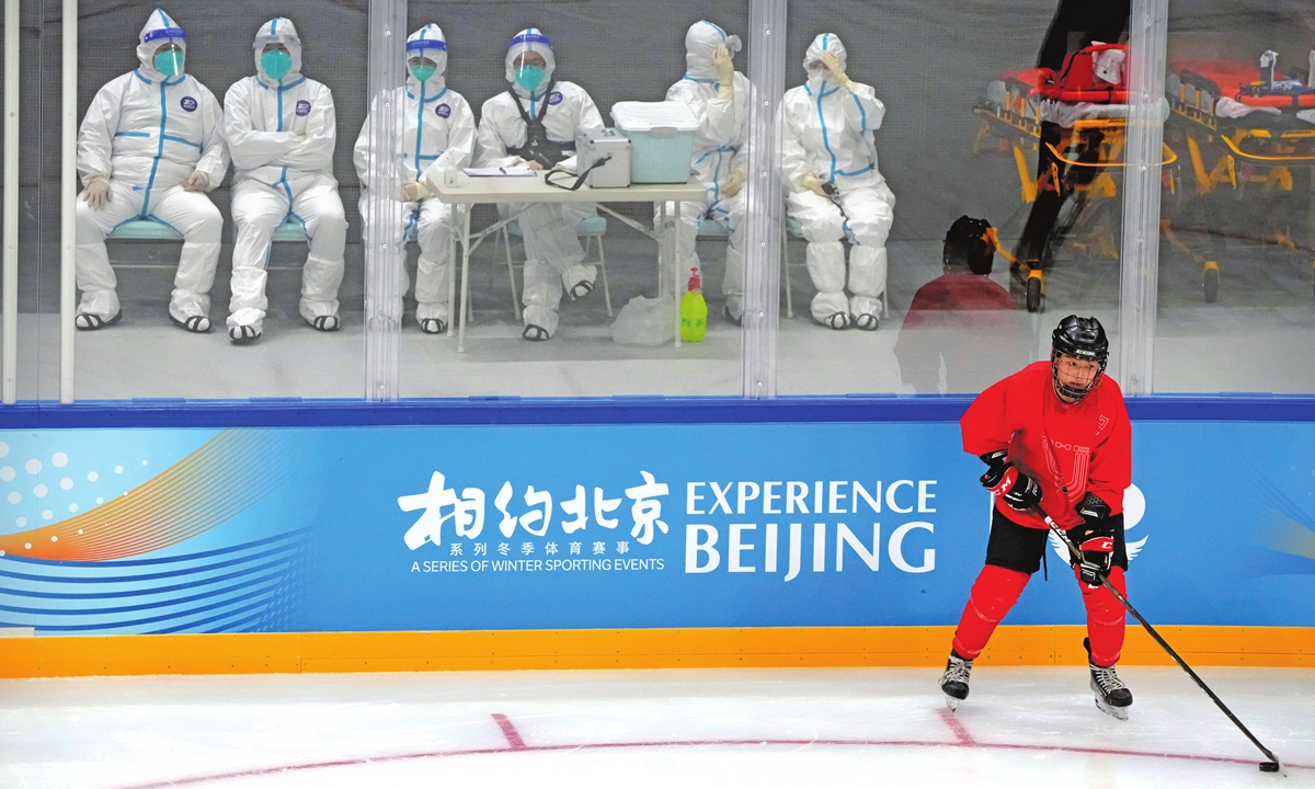 Medical personnel in protective suits watch as the China Ice Sports College hockey team practices on the ice during the Experience Beijing Ice Hockey Domestic Test Activity, a test event for the 2022 Beijing Winter Olympics, at the National Indoor Stadium in Beijing, Wednesday, November 10, 2021. Photo: VCG